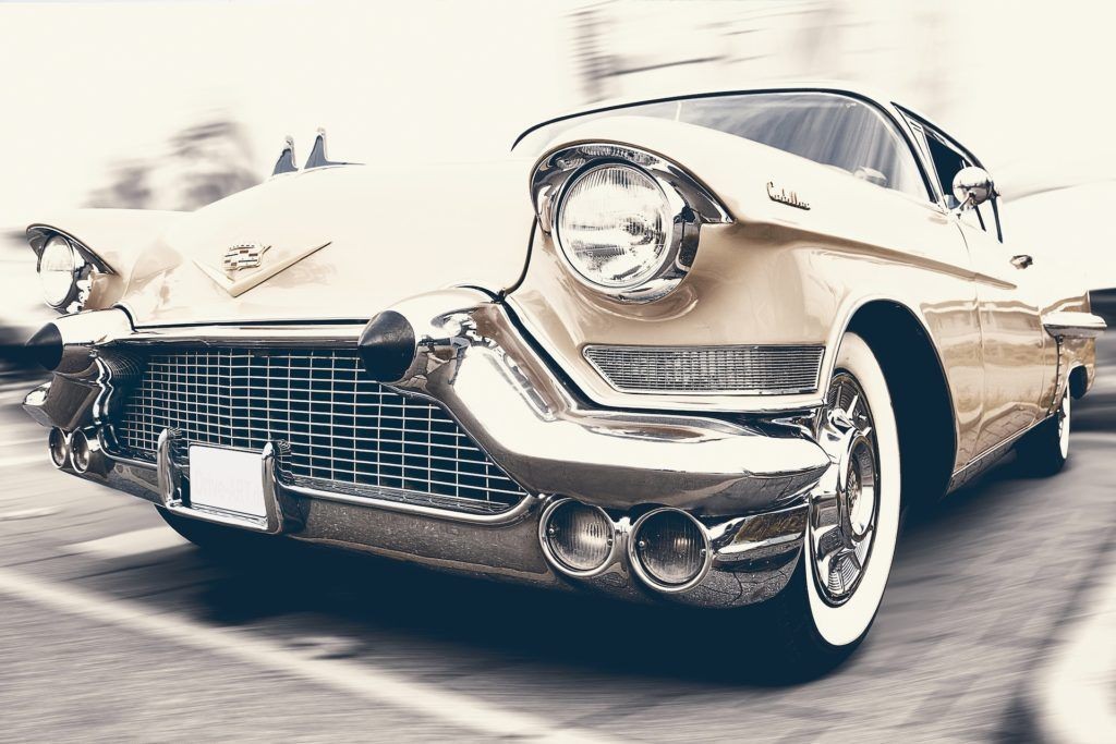 Vintage beige Cadillac with chrome details and whitewall tires, viewed from a low angle.
