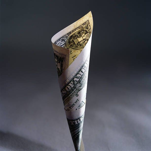A rolled US dollar bill forming a cone shape against a dark background.
